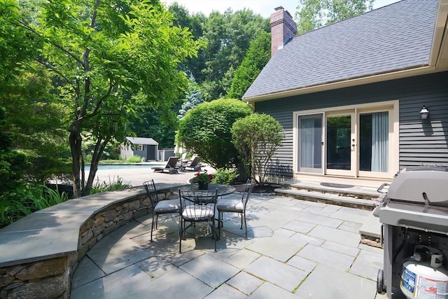 view of patio / terrace featuring outdoor dining space, an outbuilding, area for grilling, and french doors