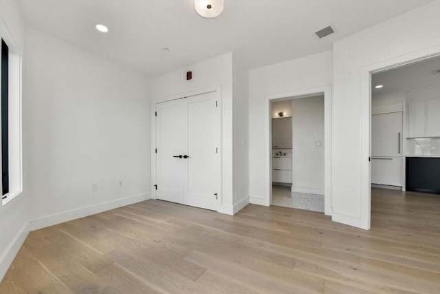 50 Leo M Birmingham Pkwy Unit 501, Boston, MA 02135 - unfurnished bedroom featuring light wood-style floors, baseboards, connected bathroom, and recessed lighting