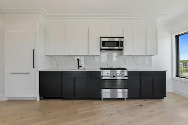 50 Leo M Birmingham Pkwy Unit 501, Boston, MA 02135 - kitchen featuring appliances with stainless steel finishes, a sink, white cabinets, ornamental molding, and tasteful backsplash