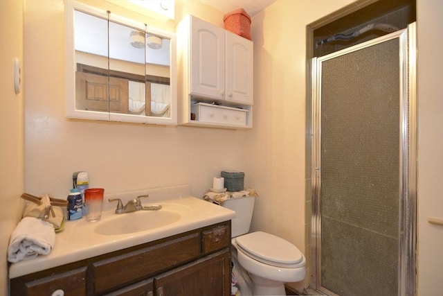 bathroom featuring vanity, a shower with door, and toilet