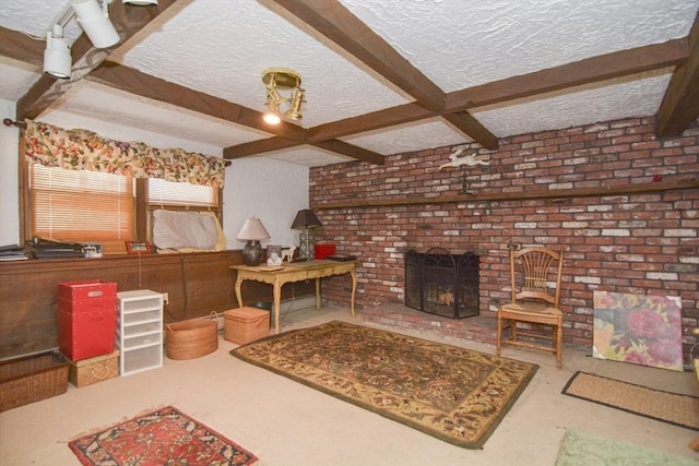 living room with a brick fireplace, beamed ceiling, and a textured ceiling