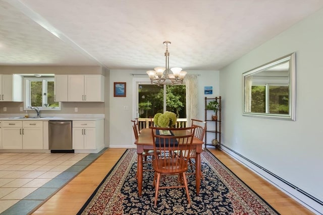 dining area with sink, light hardwood / wood-style flooring, a chandelier, and baseboard heating