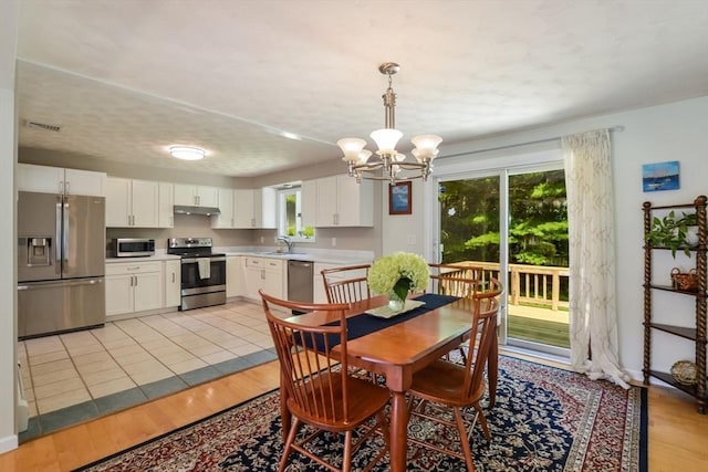 dining area featuring a notable chandelier, sink, and light tile patterned floors