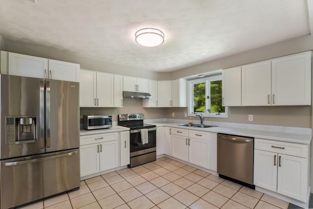 kitchen with stainless steel appliances, light tile patterned flooring, sink, and white cabinets