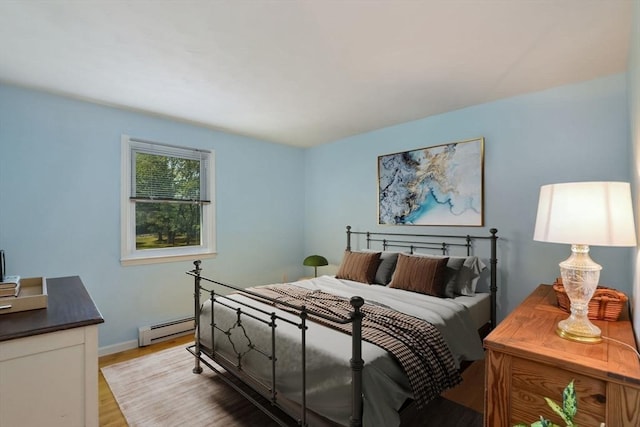 bedroom with a baseboard radiator and light hardwood / wood-style floors