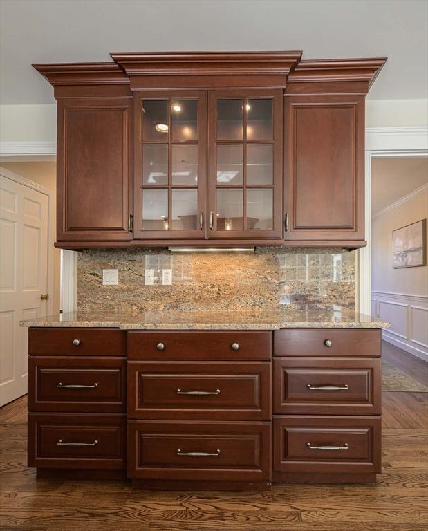 bar featuring light stone countertops, dark hardwood / wood-style floors, and backsplash