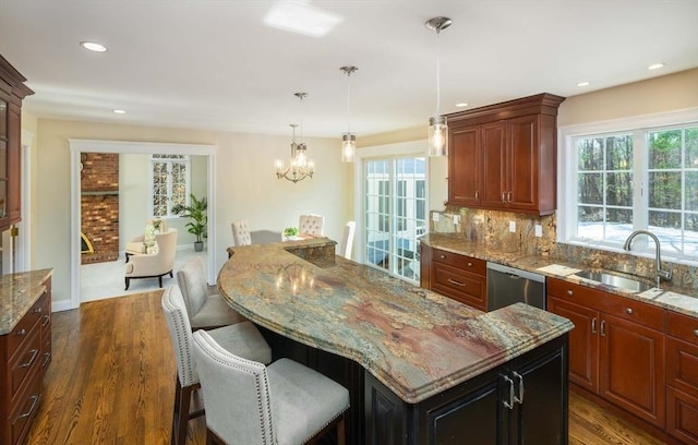 kitchen with sink, light stone counters, a center island, stainless steel dishwasher, and dark hardwood / wood-style floors