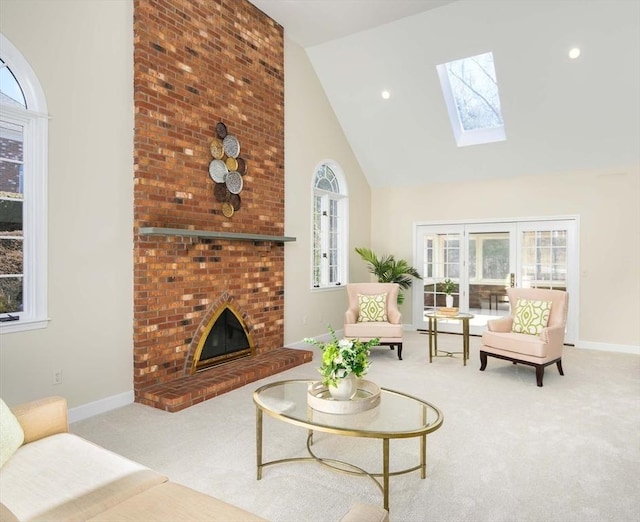 living room featuring a brick fireplace, light colored carpet, high vaulted ceiling, and a skylight