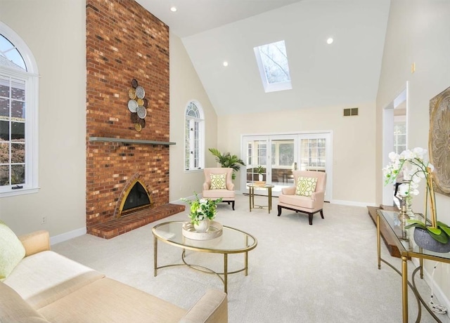 carpeted living room with a fireplace, a skylight, and high vaulted ceiling