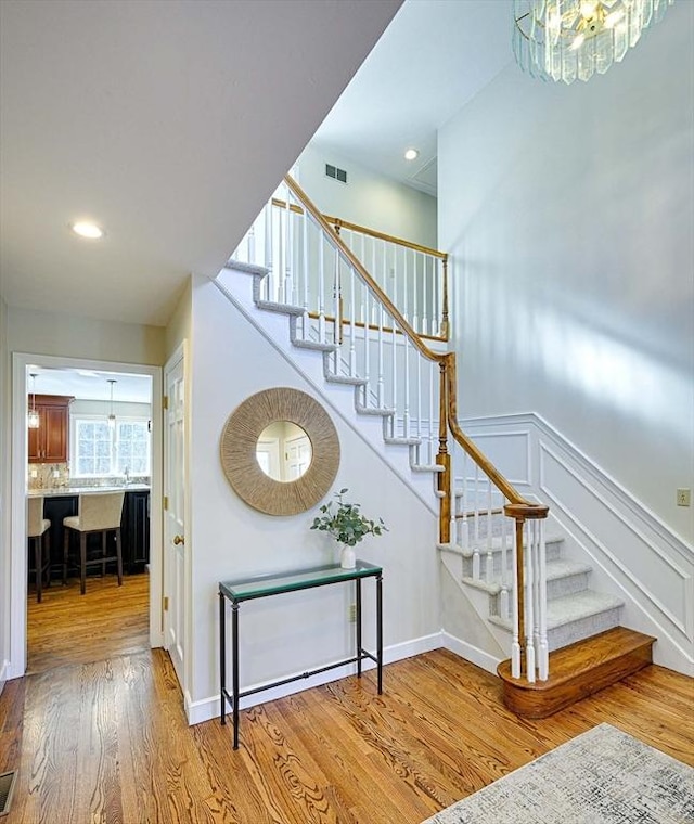 stairway with hardwood / wood-style flooring and a chandelier