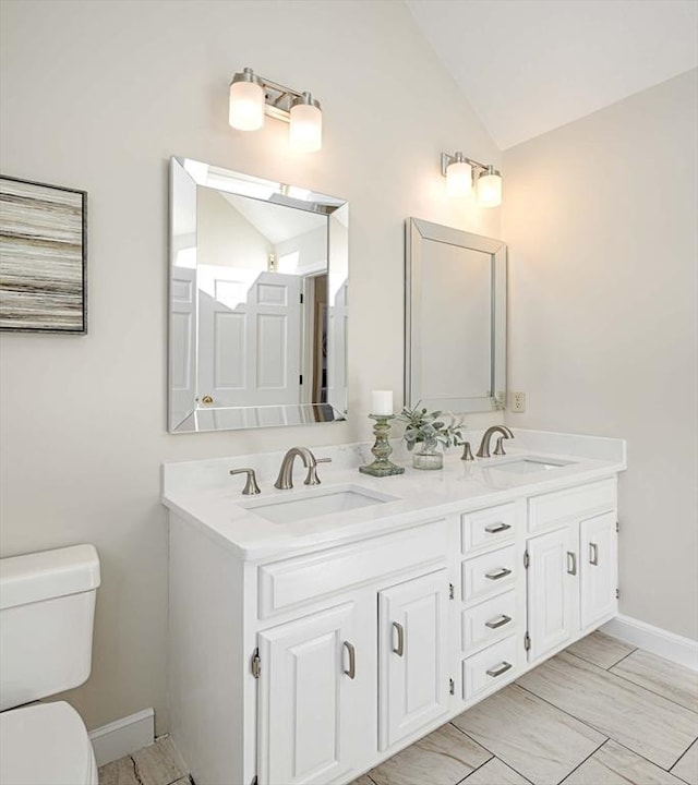 bathroom featuring vanity, toilet, and vaulted ceiling