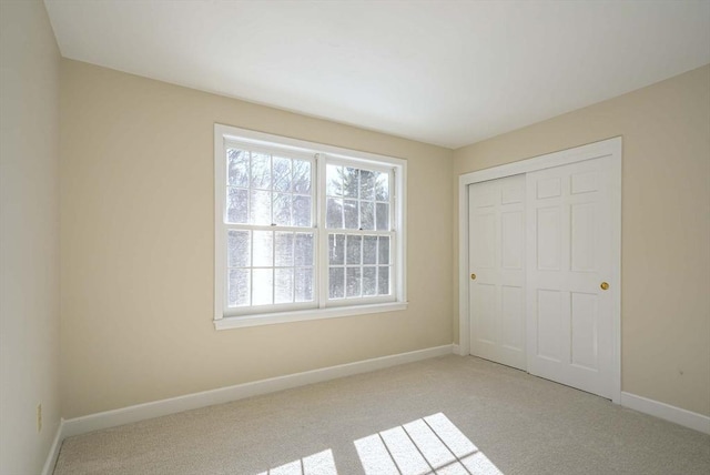 unfurnished bedroom featuring light colored carpet and a closet