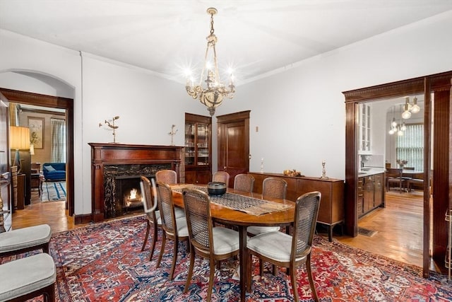 dining room with a notable chandelier, light hardwood / wood-style flooring, and a high end fireplace