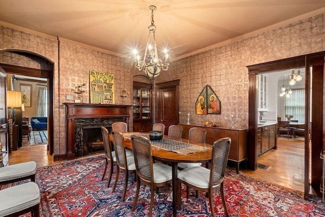 dining area with a high end fireplace, an inviting chandelier, and crown molding