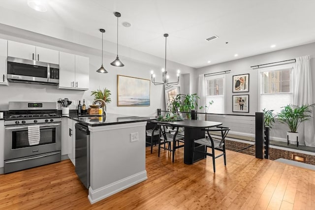 kitchen featuring sink, white cabinetry, light hardwood / wood-style floors, kitchen peninsula, and stainless steel appliances