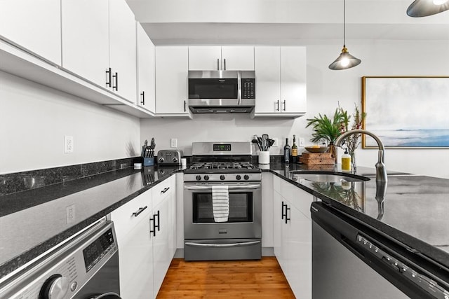 kitchen featuring white cabinets, appliances with stainless steel finishes, washer / dryer, and sink