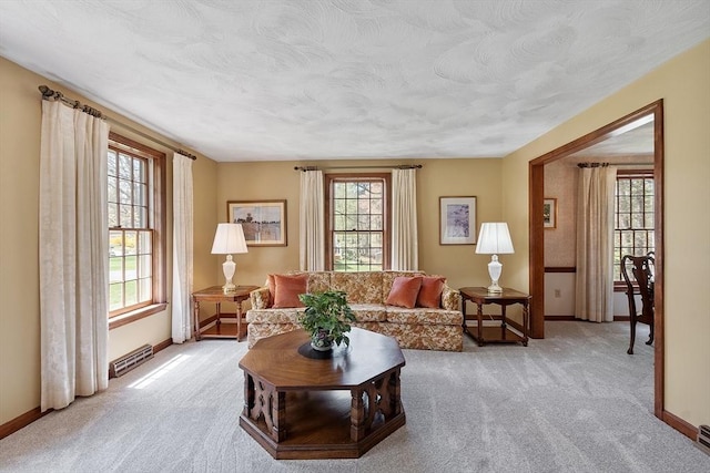 living area featuring baseboards, light colored carpet, and a wealth of natural light