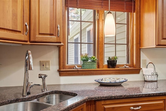kitchen featuring brown cabinets, a sink, and dark stone countertops