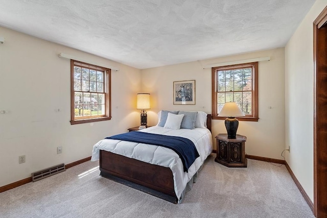 bedroom featuring carpet floors, a textured ceiling, baseboards, and visible vents