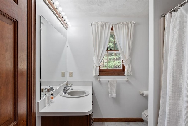 full bath with toilet, baseboards, a shower with shower curtain, and vanity