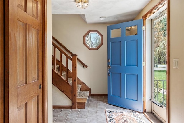 foyer with stairway, baseboards, and light tile patterned flooring
