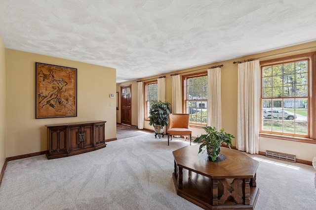sitting room with visible vents, a textured ceiling, baseboards, and carpet floors