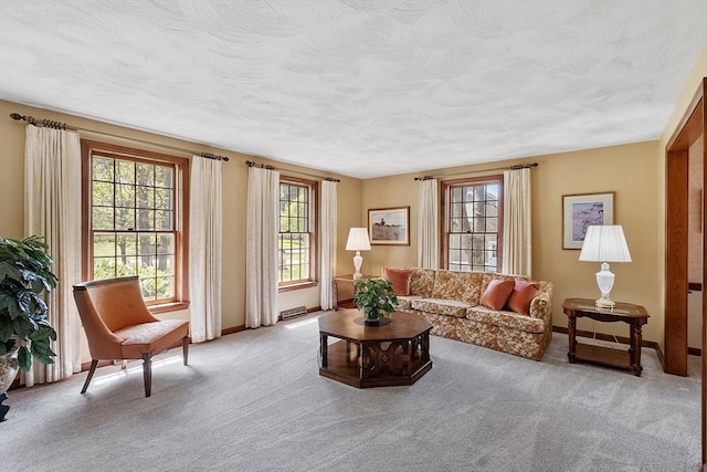 living room with a textured ceiling, baseboards, light colored carpet, and visible vents