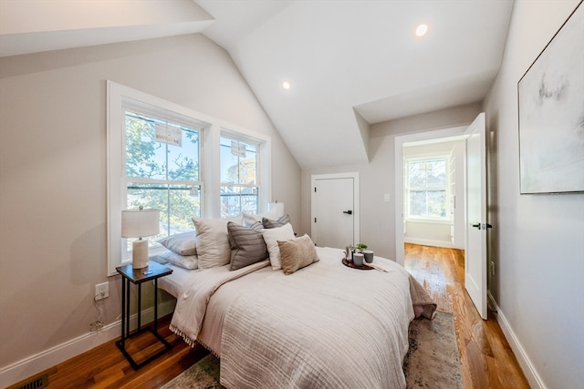 bedroom with wood-type flooring, multiple windows, and lofted ceiling