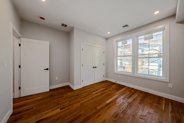 unfurnished bedroom featuring dark hardwood / wood-style flooring and a closet