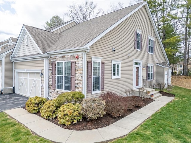 23 Kendall Ct Unit 23, Bedford, MA 01730 - view of home's exterior with aphalt driveway, a yard, roof with shingles, stone siding, and an attached garage