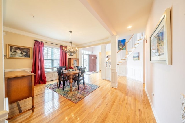 23 Kendall Ct Unit 23, Bedford, MA 01730 - dining area featuring a notable chandelier, ornate columns, crown molding, and light wood-style flooring