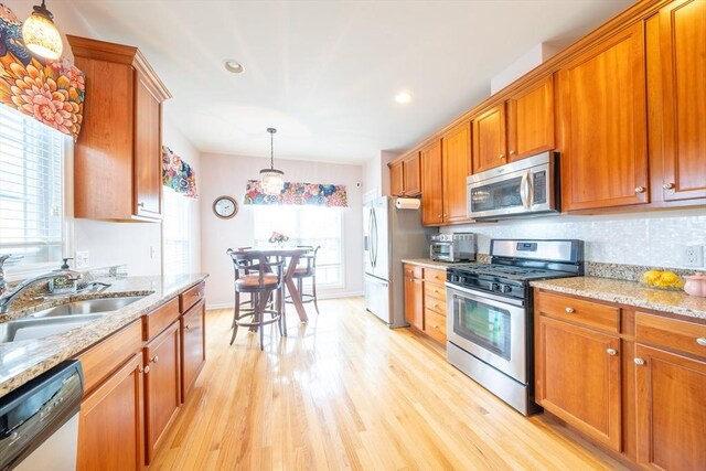 23 Kendall Ct Unit 23, Bedford, MA 01730 - kitchen featuring stainless steel appliances, brown cabinetry, a sink, and light wood-style flooring