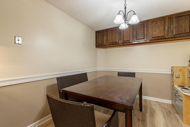 dining room featuring a chandelier, light hardwood / wood-style floors, and lofted ceiling