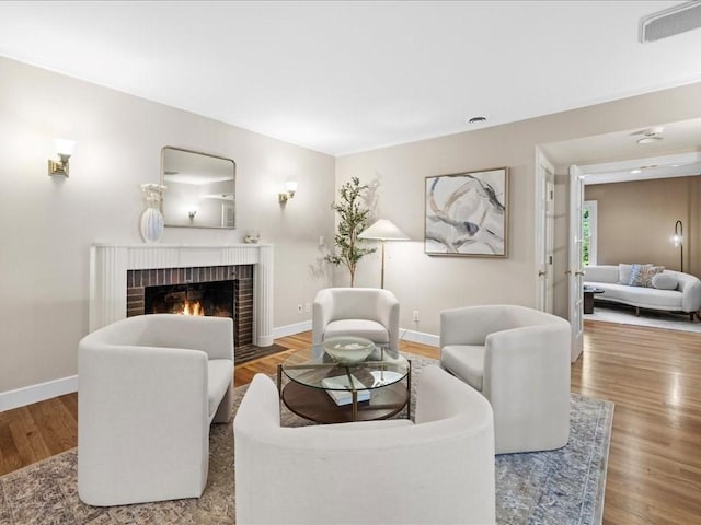 living room featuring hardwood / wood-style flooring and a brick fireplace