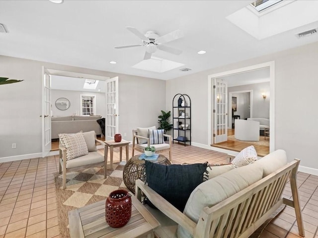 living room featuring a skylight, light tile patterned flooring, and french doors