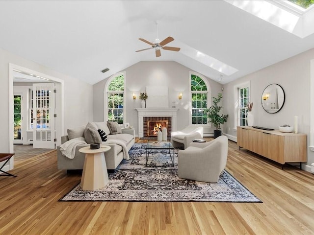 living room with vaulted ceiling, a brick fireplace, a baseboard radiator, hardwood / wood-style flooring, and ceiling fan