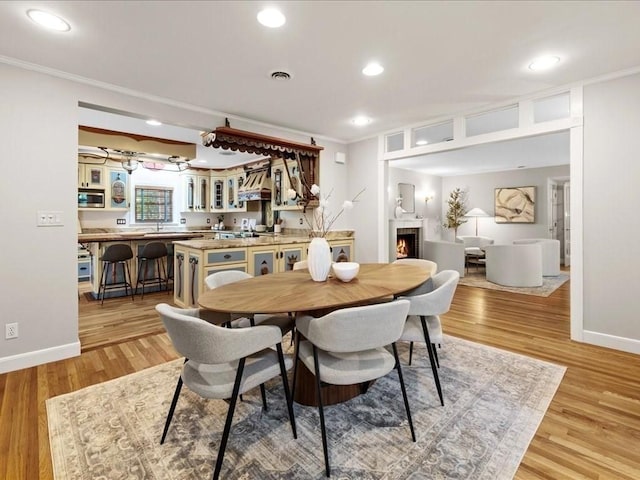 dining space featuring crown molding and light hardwood / wood-style flooring