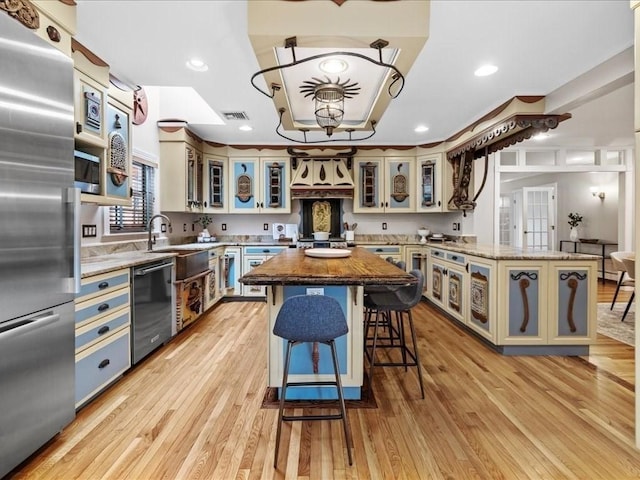 kitchen featuring light stone countertops, a kitchen island, sink, and built in appliances