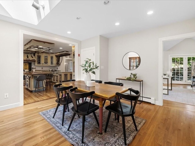 dining area with lofted ceiling, light hardwood / wood-style flooring, french doors, and baseboard heating