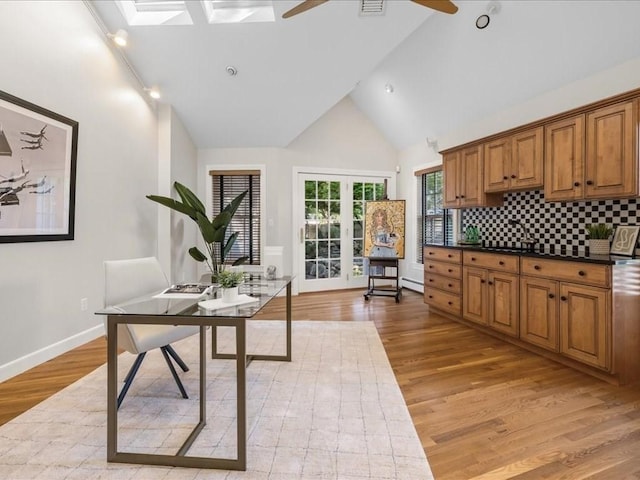 kitchen with ceiling fan, high vaulted ceiling, decorative backsplash, and light wood-type flooring