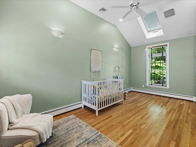 bedroom with a baseboard radiator, wood-type flooring, and lofted ceiling with skylight