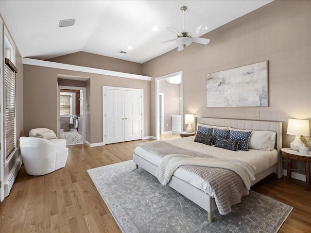 bedroom featuring vaulted ceiling, connected bathroom, a baseboard heating unit, ceiling fan, and light hardwood / wood-style flooring