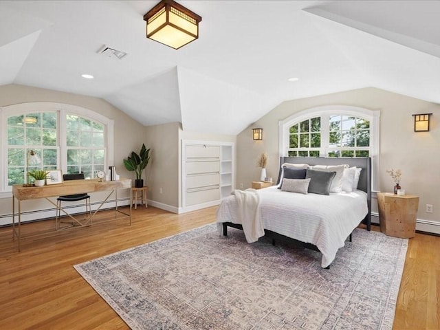 bedroom featuring lofted ceiling, hardwood / wood-style floors, and a baseboard heating unit