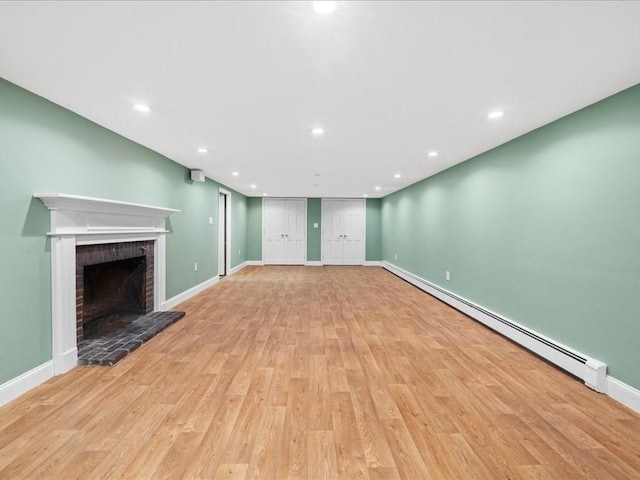 unfurnished living room with a baseboard heating unit, a fireplace, and light hardwood / wood-style floors