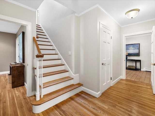 staircase featuring hardwood / wood-style flooring, crown molding, and baseboard heating