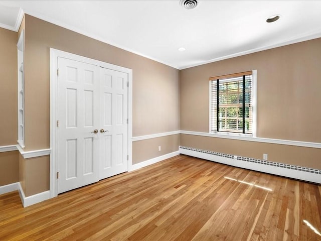 unfurnished bedroom with light hardwood / wood-style flooring, ornamental molding, a closet, and baseboard heating