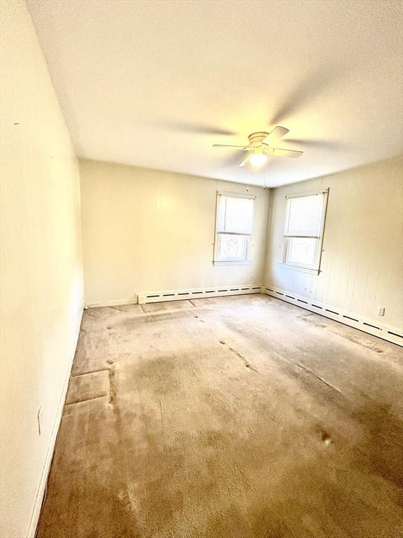 empty room with a baseboard heating unit, ceiling fan, and a textured ceiling