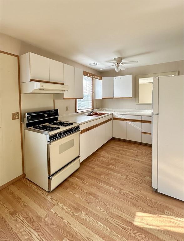 kitchen featuring white appliances, light wood-type flooring, ceiling fan, and white cabinets