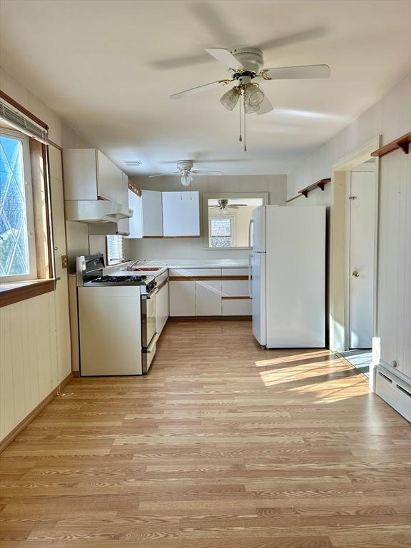 kitchen with light hardwood / wood-style floors, stainless steel gas range oven, a healthy amount of sunlight, white refrigerator, and white cabinets