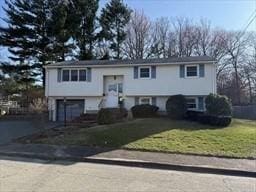 split foyer home with aphalt driveway, an attached garage, and a front yard